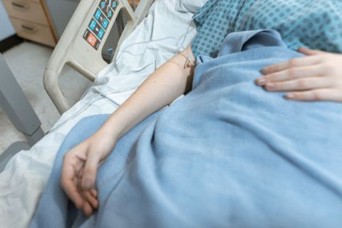 Paciente em repouso em leito hospitalar, com soro e grade da cama, sem identificação do rosto